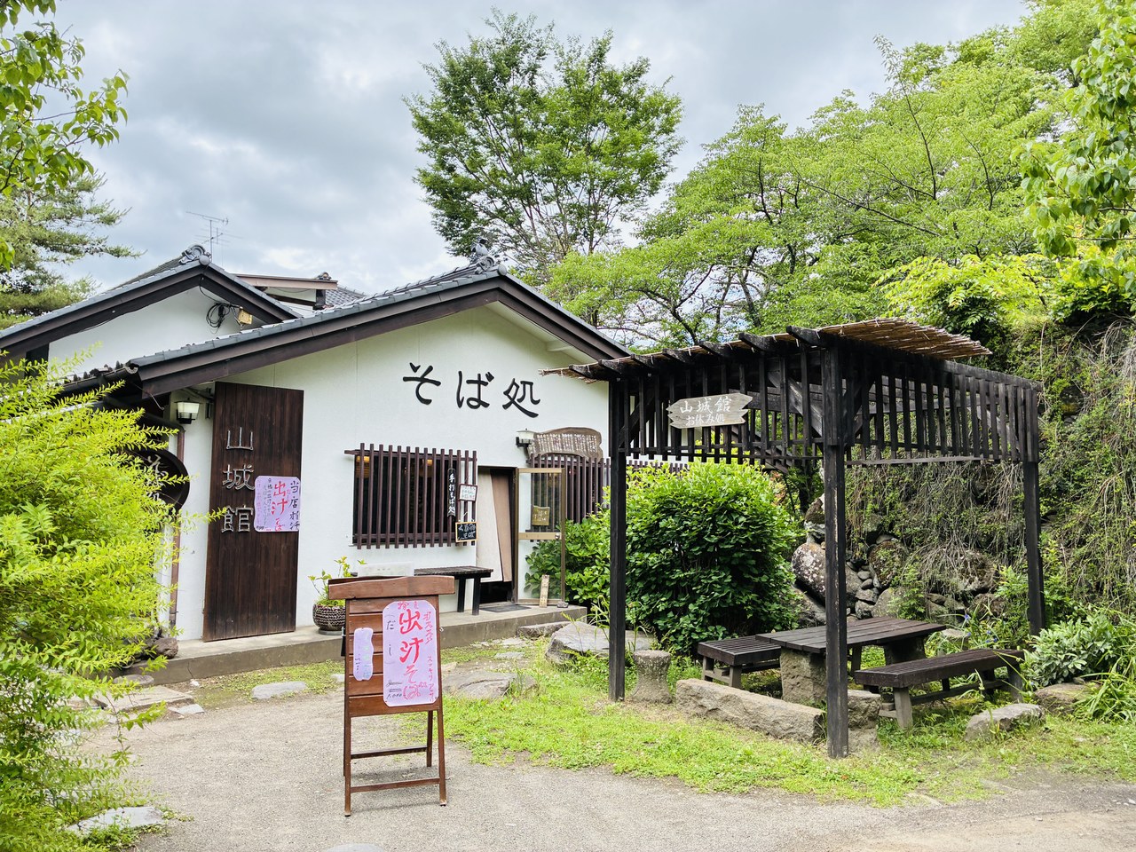 懐古園内の「そば処 山城館」。白壁の建物と藤棚、ベンチのある落ち着いたたたずまい