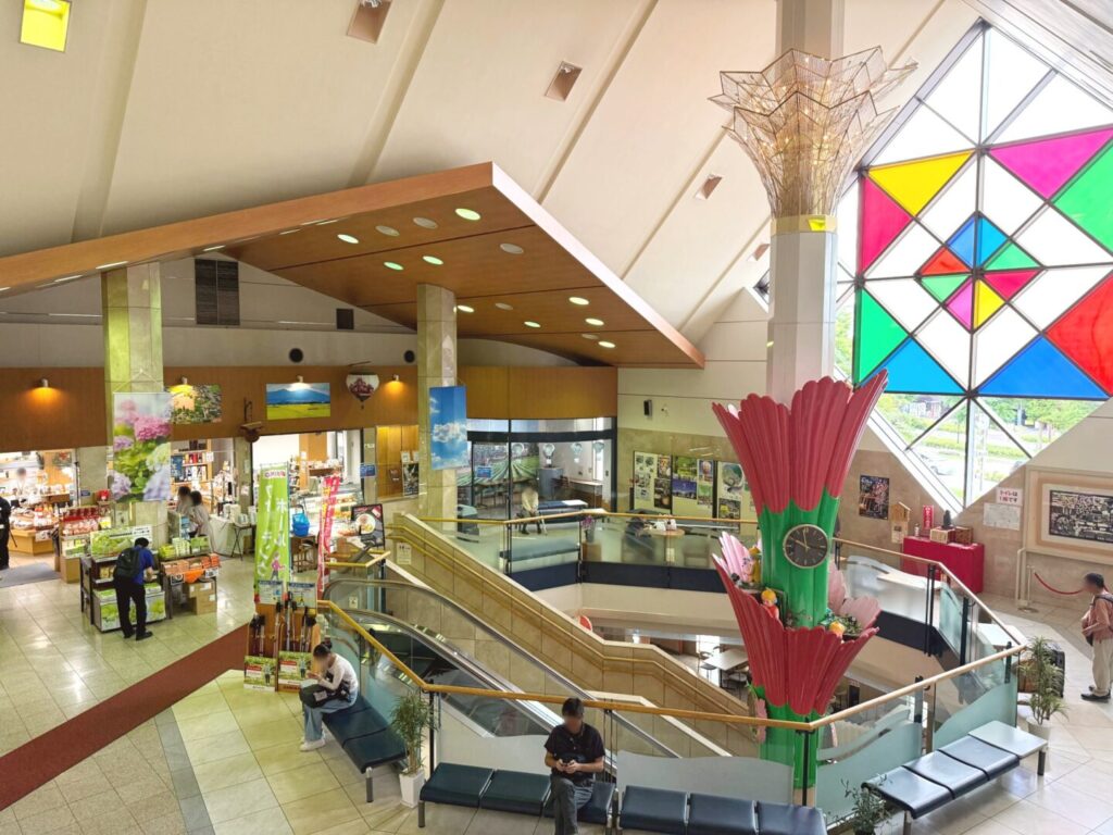 佐久平駅前プラザ佐久の館内。吹き抜けとステンドグラス、赤い花のオブジェ