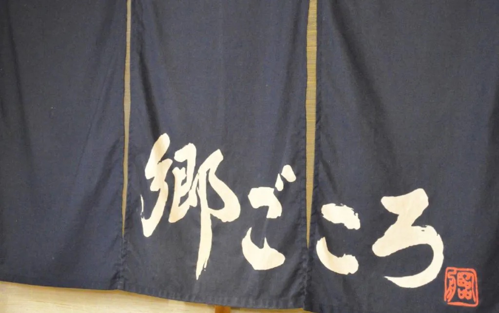 「郷ごころ」と白い文字で染め抜かれた紺色ののれん