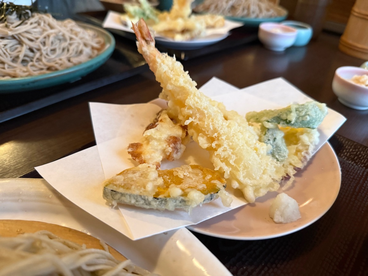 郷ごころの天ぷら。衣がサクサクの大きな海老天と、かぼちゃなどの野菜天が白い紙を敷いたお皿に盛られている