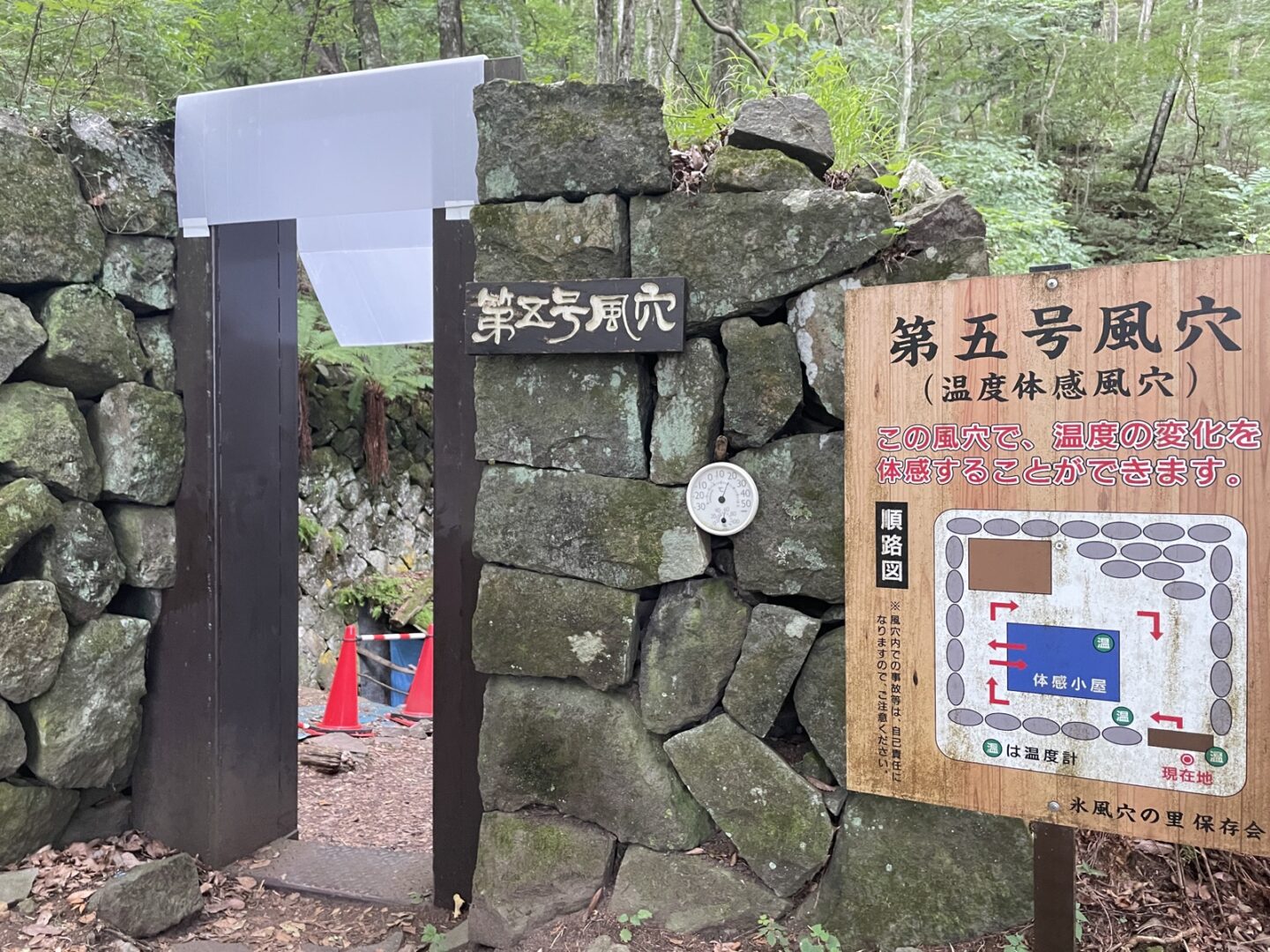 石積みの「第五号風穴(温度体感風穴)」の入口。順路図の看板が立ち、温度の変化を体感できると案内されている