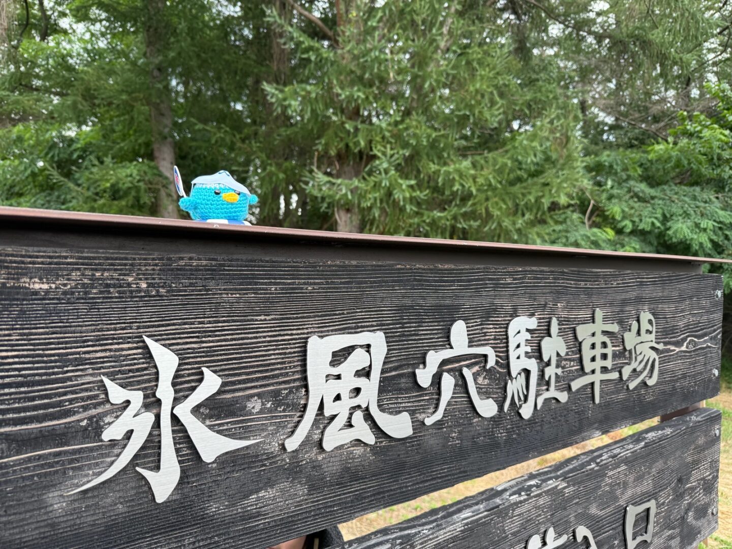 「氷風穴駐車場」と書かれた木製の看板。上にエールくんのマスコットがちょこんとのっている