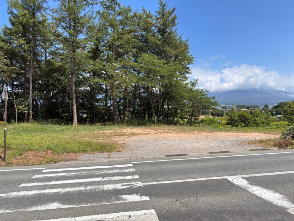 直売所の向かい側にある砂利の駐車場と、奥に見える浅間山