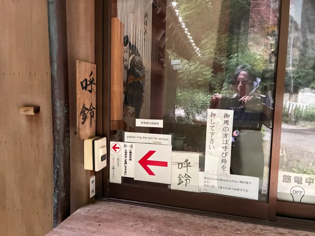 社務所の入口に貼られた「御用の方は呼び鈴を押して下さい」の貼り紙と呼び鈴