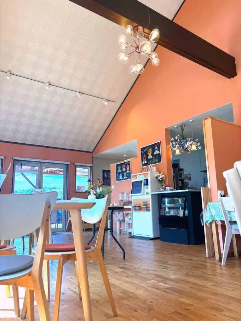 佐久市内山のカフェ花水木の明るい店内。オレンジの壁とシャンデリア照明、木目の家具が並ぶ