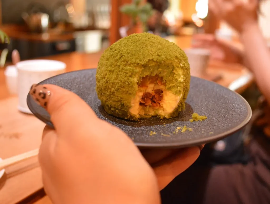 緑の苔のようなスポンジでおおわれ、断面からクリームがのぞく苔玉ケーキ