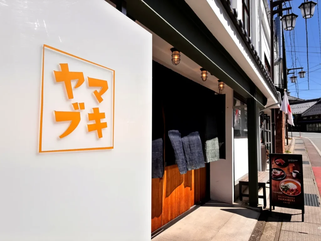 オレンジの「ヤマブキ」の看板があるデリカテッセン山吹の外観