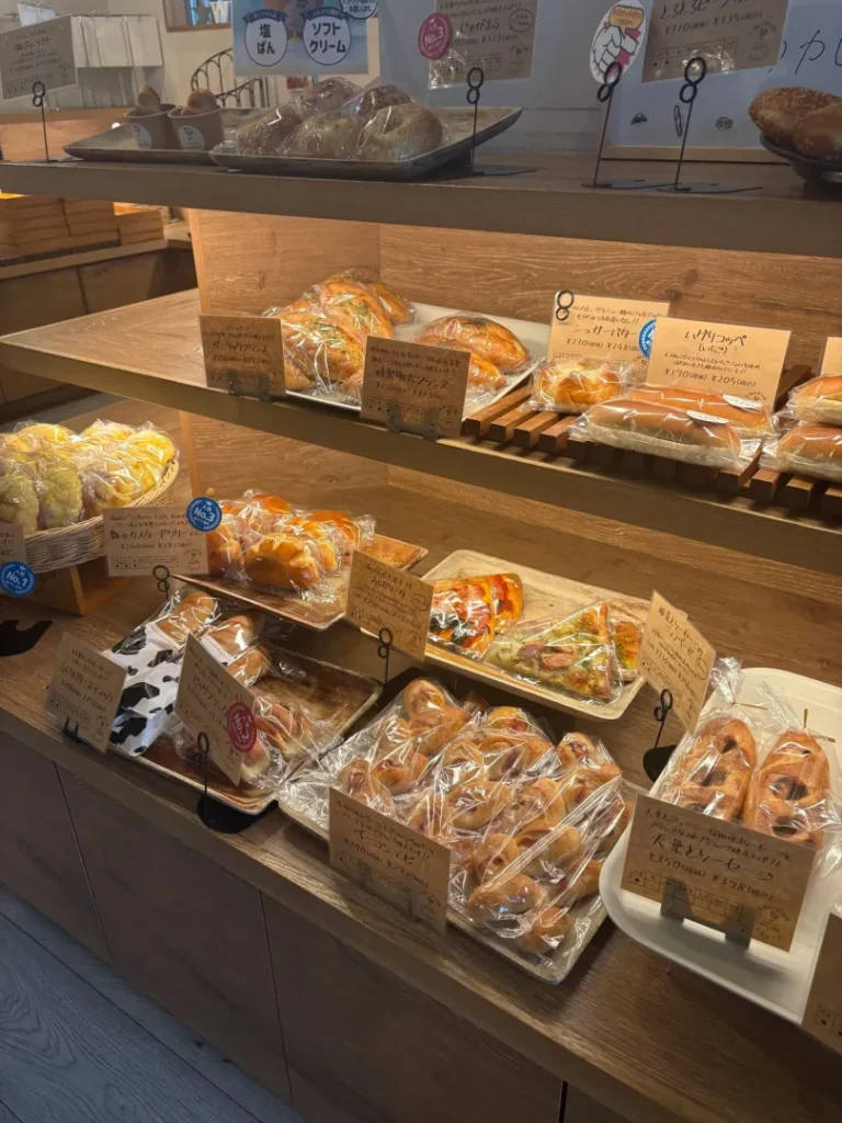 ハグリコの店内の棚に並ぶ、袋入りのおかずパンや甘いパン